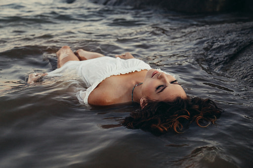 Woman in white shirt floating in ocean | TOP 25 health and wellness rituals to nurture your body and mind