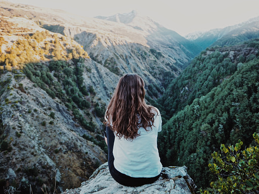 Woman sitting atop a mountain | Fall bucket list 10 impactful fall activities