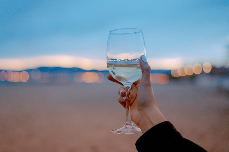 Woman holding white wine glass against desert | 10 best holiday gift ideas for meaningful gifts