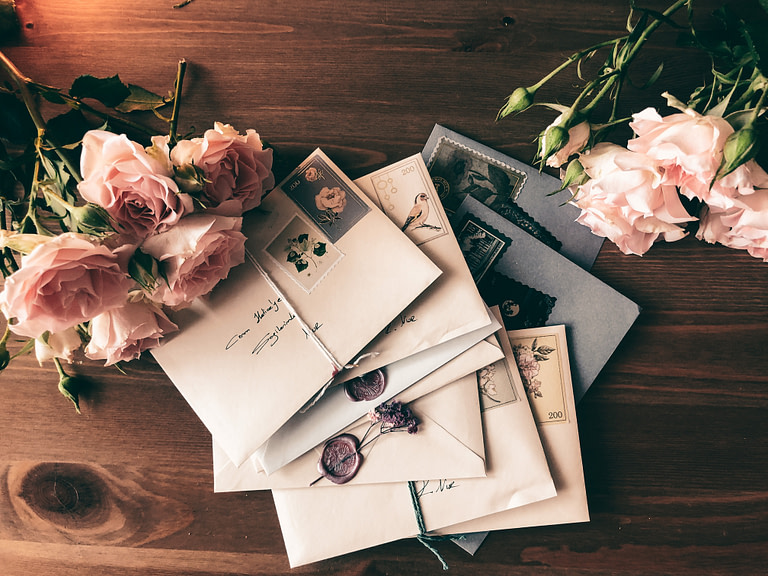 Hand written letters on a desk with bouquets of roses | 10 best holiday gift ideas for meaningful gifts