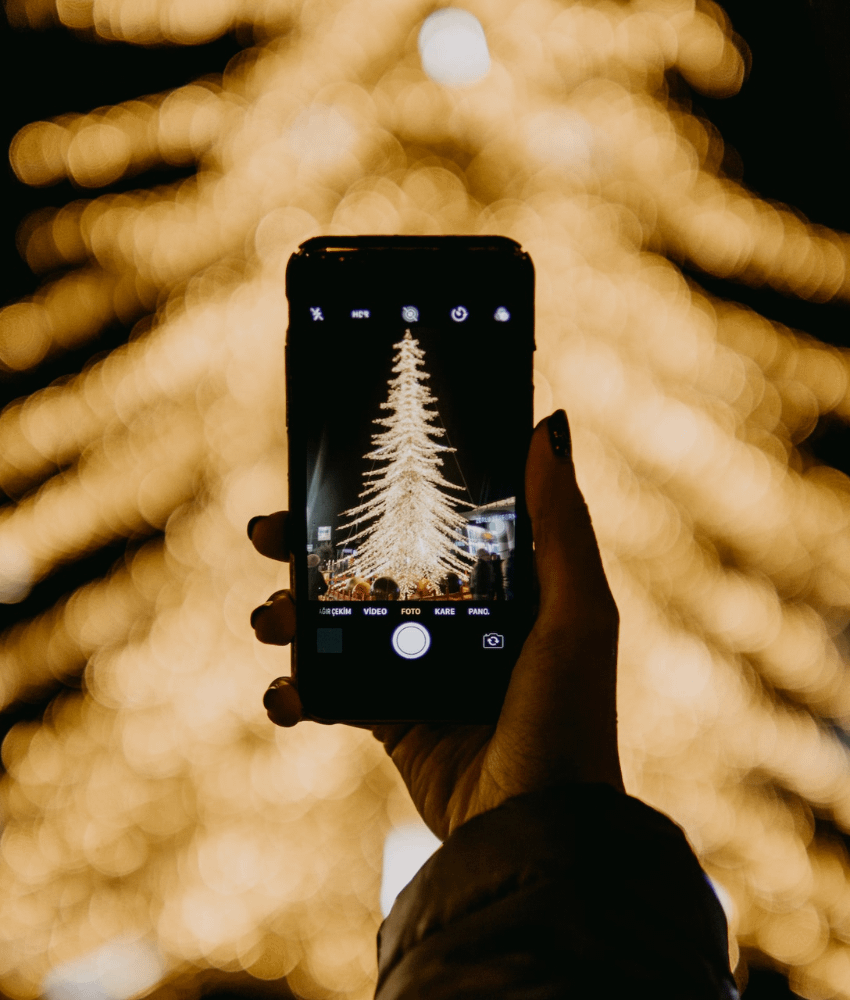 Hand holding phone camera with the christmas tree